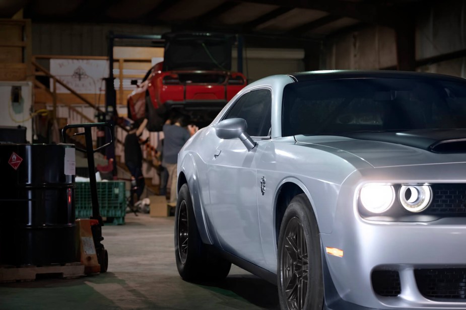Promo photo of a SRT Dodge Demon parked in a garage, a red Challenger behind it.