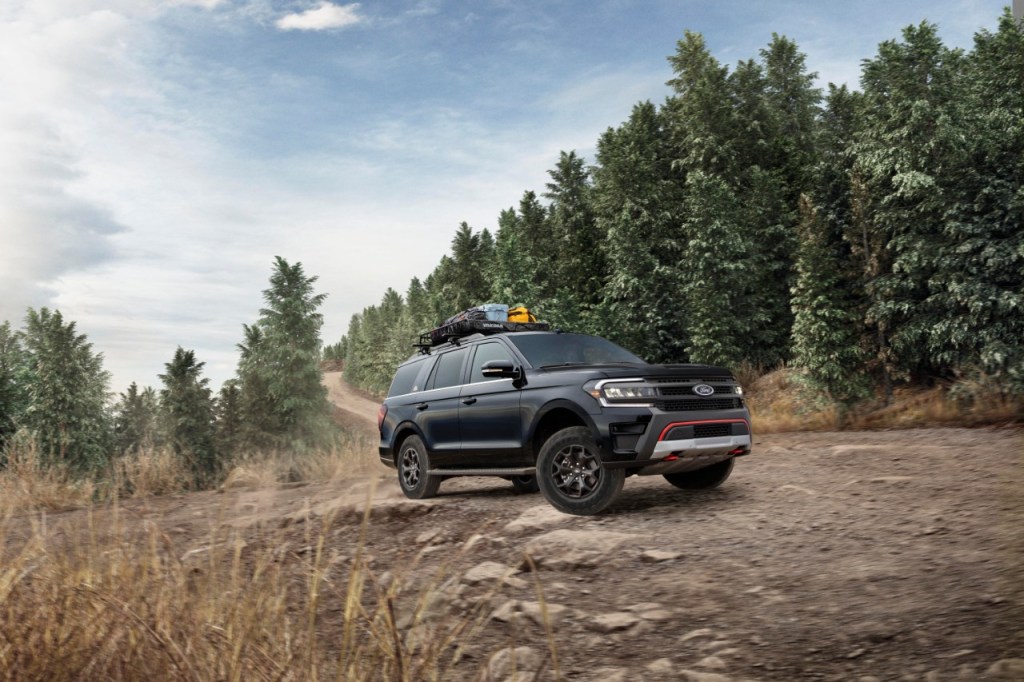 A black Expedition Timberline driving off-road with trees in the background. 