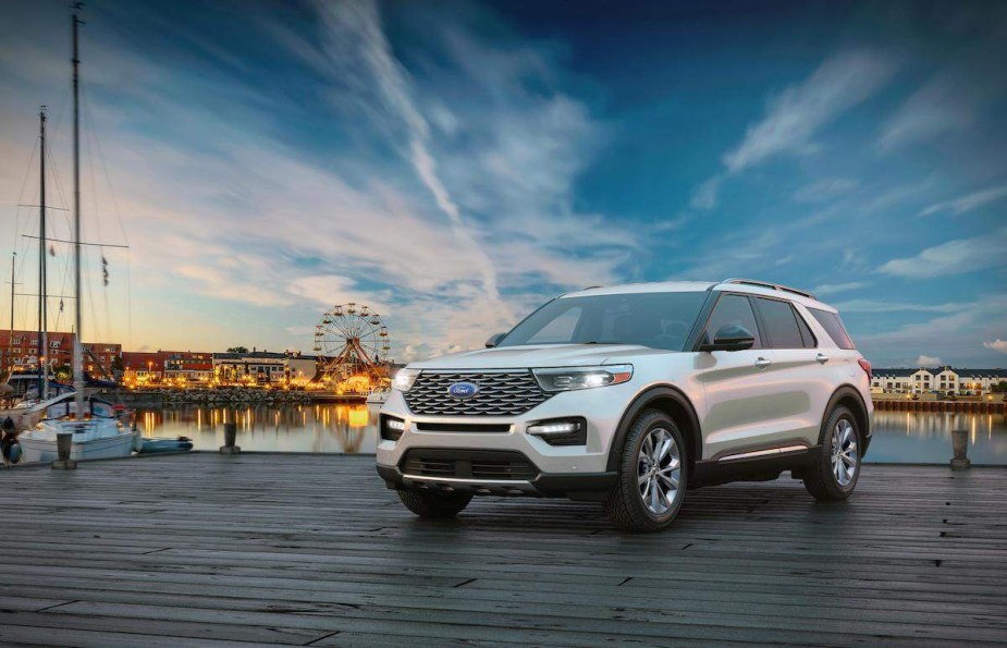 A white 2023 Ford Explorer Hybrid, which is the best hybrid Ford, parked close to a pier. 