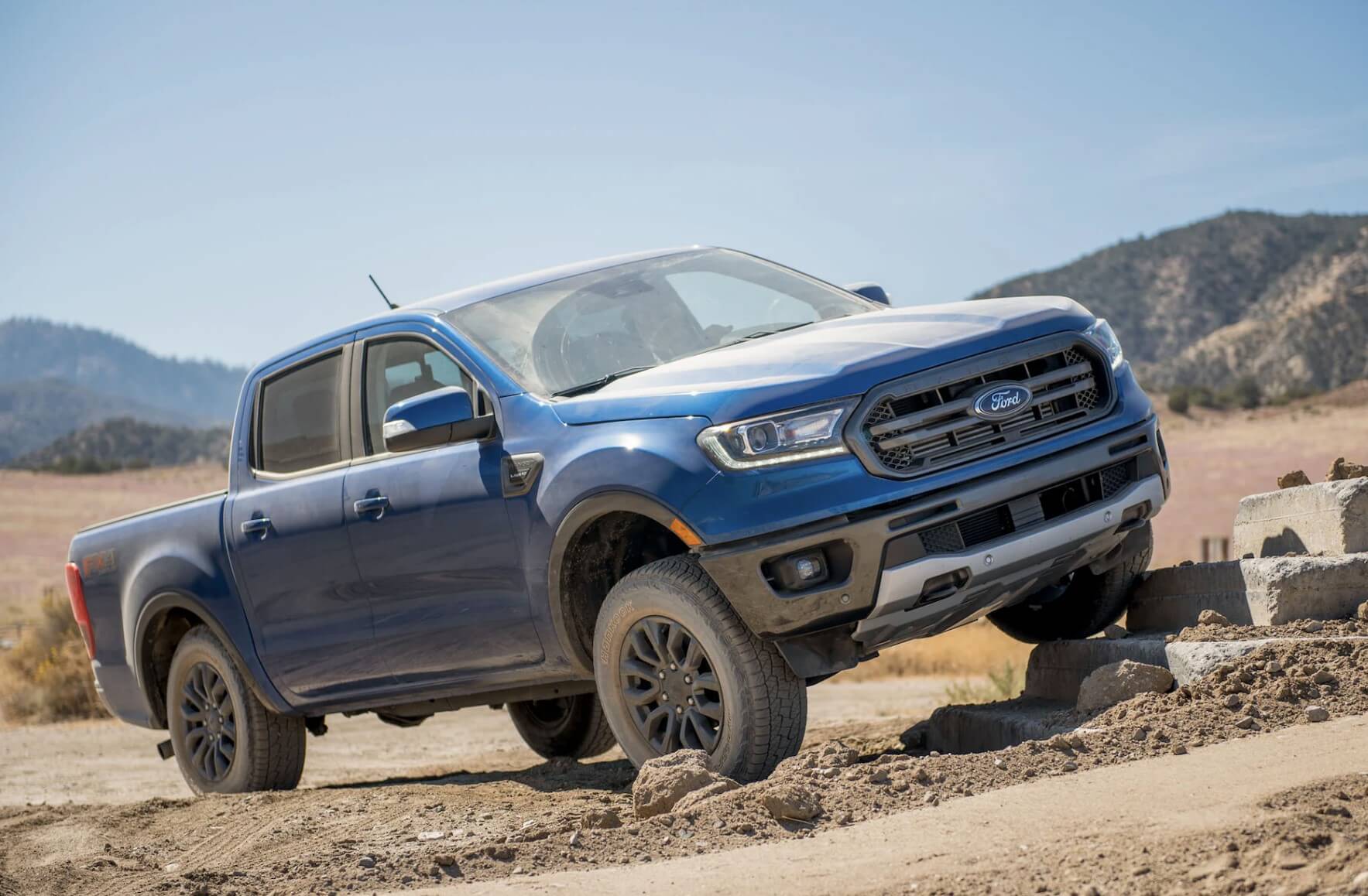 A blue 2023 Ford Ranger driving off-road. The 2023 Ford Ranger interior leaves a lot to be desired.