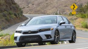 A silver 2023 Honda Civic, buoyed by its Top Safety Pick rating, takes a corner at speed.