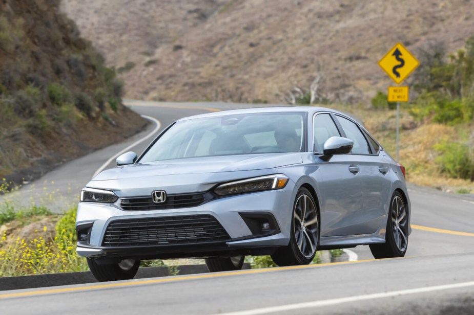 A silver 2023 Honda Civic, buoyed by its Top Safety Pick rating, takes a corner at speed.  