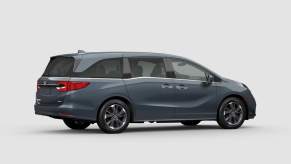 A light blue 2023 Honda Odyssey in a whit room.