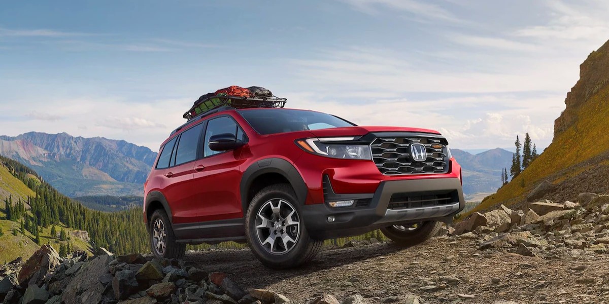 A red 2023 Honda Passport midsize SUV is driving off-road.
