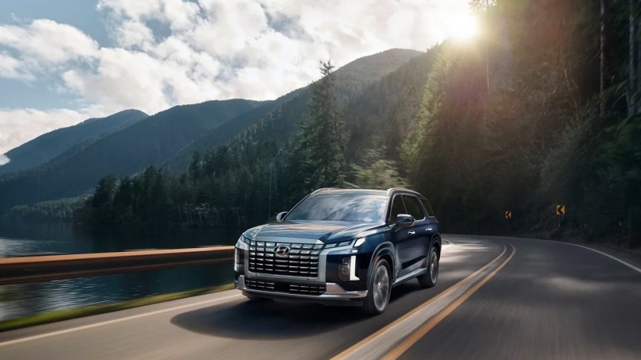 A blue 2023 Hyundai Palisade Calligraphy is driving on the road.