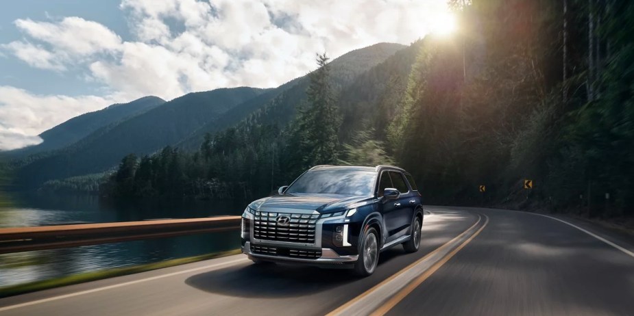 A blue 2023 Hyundai Palisade Calligraphy is driving on the road. 