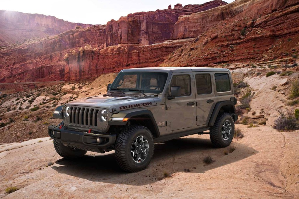 A 2023 Jeep Wrangler Rubicon scales red rocks in the desert. It's rated as one of the most reliable American SUVs of 2023.