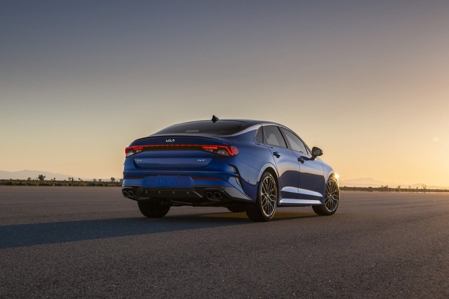 A blue 2023 Kia K5 LXS shows off its rear-end styling at sunset. 