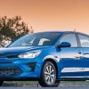 Blue 2023 Kia Rio Hatchback posed with a sunset background