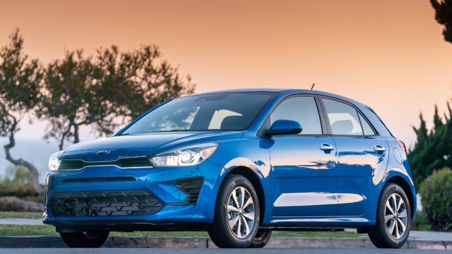Blue 2023 Kia Rio Hatchback posed with a sunset background