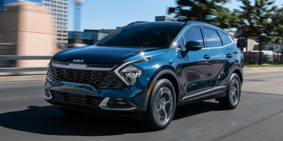 A blue 2023 Kia Sportage Hybrid small hybrid SUV is driving on the road.