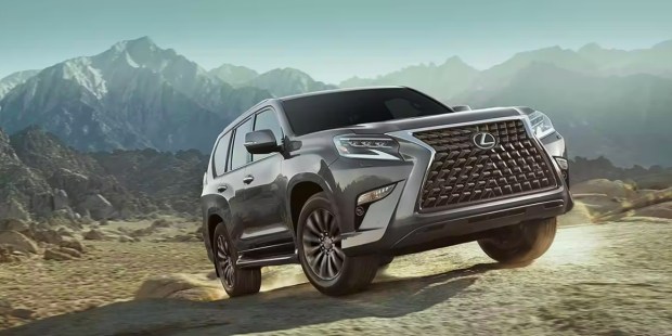 A gray 2023 Lexus GX full-size luxury SUV is driving off-road.
