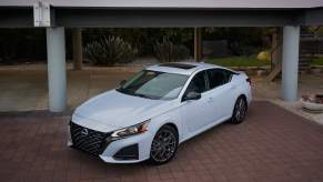 A white 2023 Nissan Altima parked in front of a building.