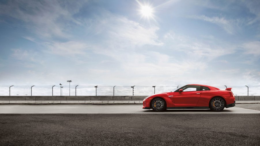 A red 2023 Nissan GT-R, also known as Godzilla, shows off its side profile on a race track.