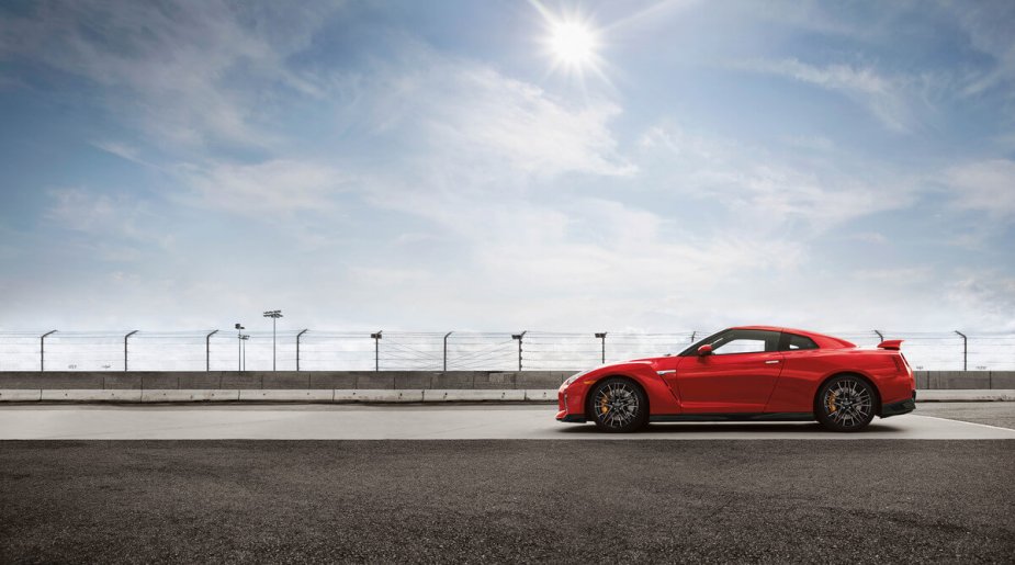 A red 2023 Nissan GT-R, also known as Godzilla, shows off its side profile on a race track. 