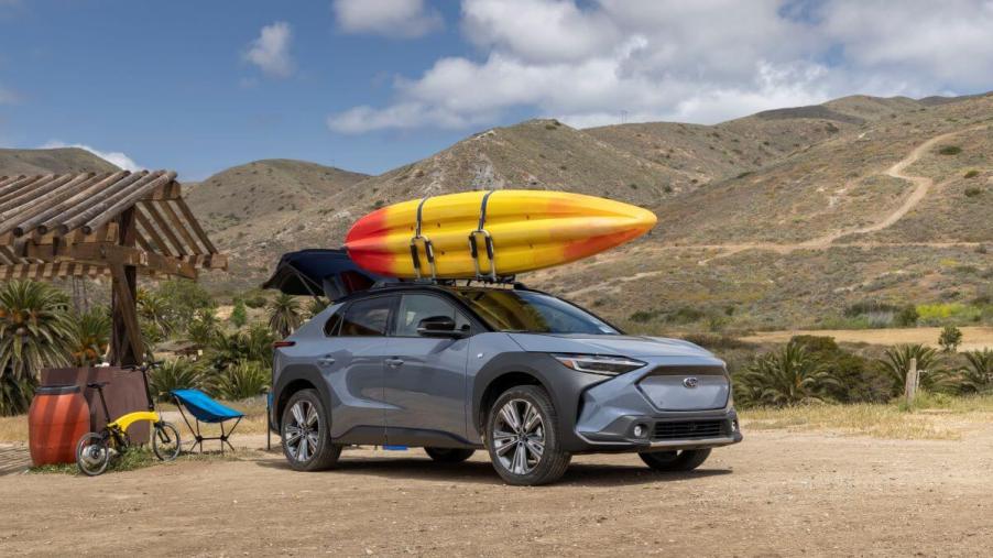 A blue 2023 Subaru Solterra electric compact SUV model with a yellow kayak strapped to its roof rack