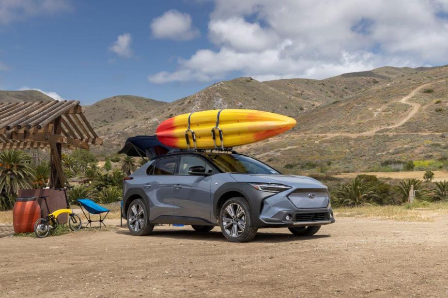 A blue 2023 Subaru Solterra electric compact SUV model with a yellow kayak strapped to its roof rack
