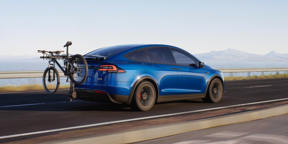 A blue 2023 Tesla Model X Plaid midsize SUV is driving on the road. 
