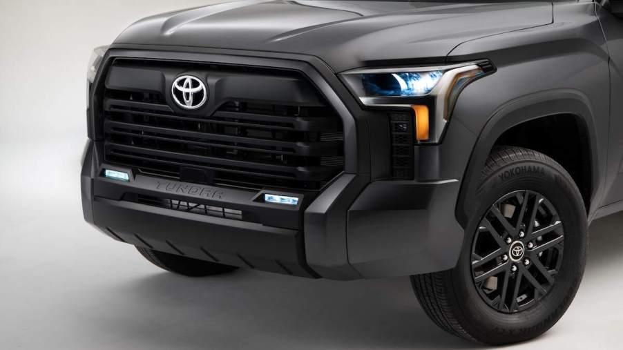 A silver 2023 Toyota Tundra, which is the Toyota that is the best, grille and headlights against a white background.