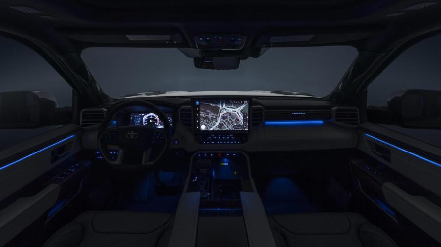 The interior of a 2023 Toyota Tundra at night with its infotainment touch screen and digital gauge cluster illuminated.