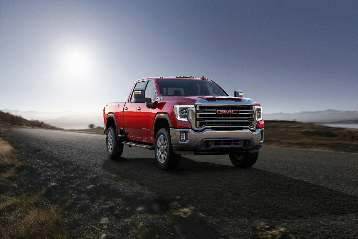A red 2023 GMC Sierra 2500HD driving down a gravel road. This is one of the most reliable used pickup trucks.