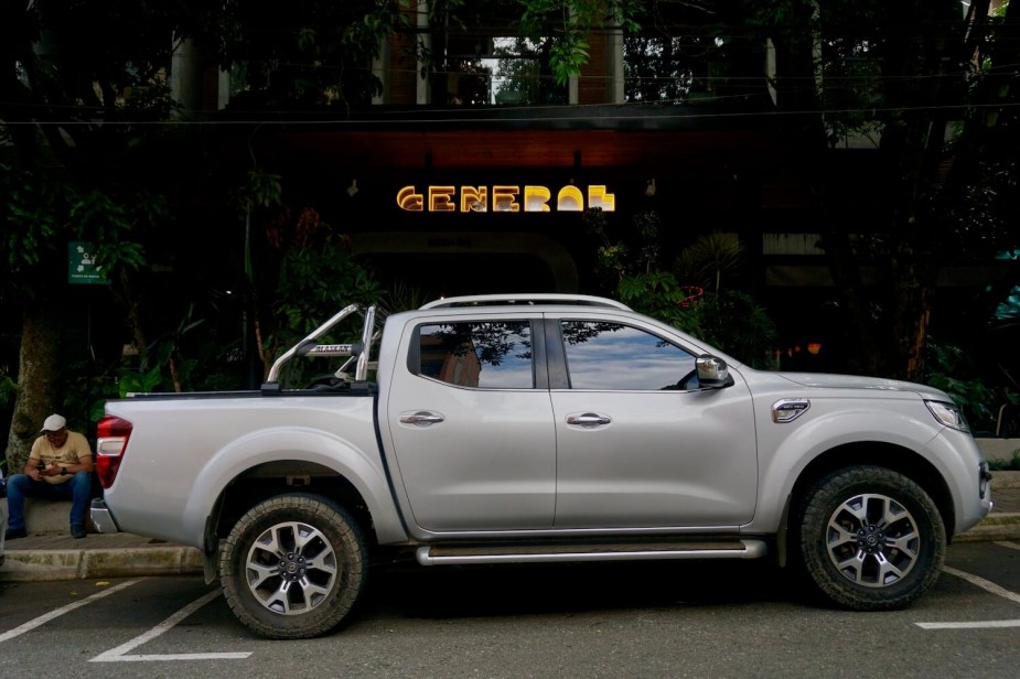 Profile view of the Renault Alaskan midsize pickup truck, based on the Nissan Frontier, parked in front of a hotel in Colombia.