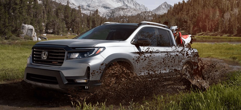 A 2023 Honda Ridgeline midsize truck kicks up mud.