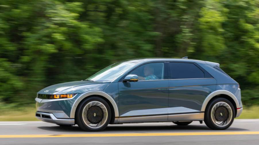 A 2023 Hyundai Ioniq 5 electric SUV rolls down a road with blurred greenery in the background. It's the lowest rated 2023 compact SUV according to J.D. Power