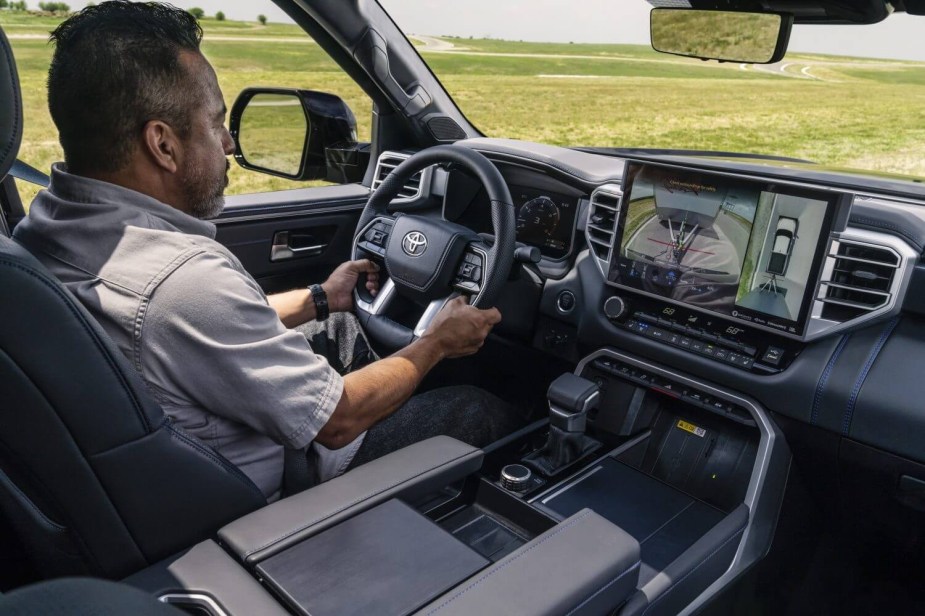 A man looks at the backup camera of a 2023 Toyota Tundra while he is pulling a heavy trailer.