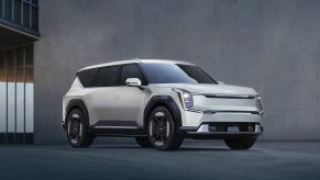 A gray 2024 Kia EV9 midsize electric SUV is parked in front of a gray wall.