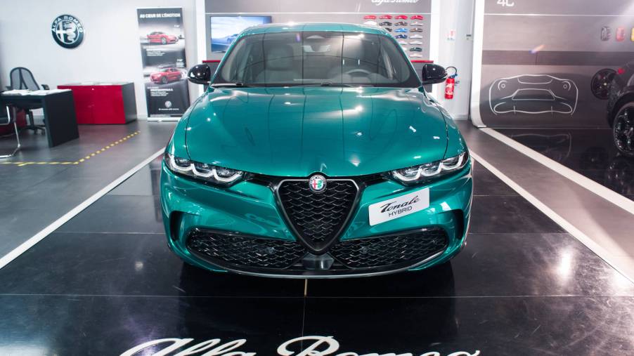 A green Alfa Romeo Tonale sits on a showroom floor with the Alfa Romeo logo in front.