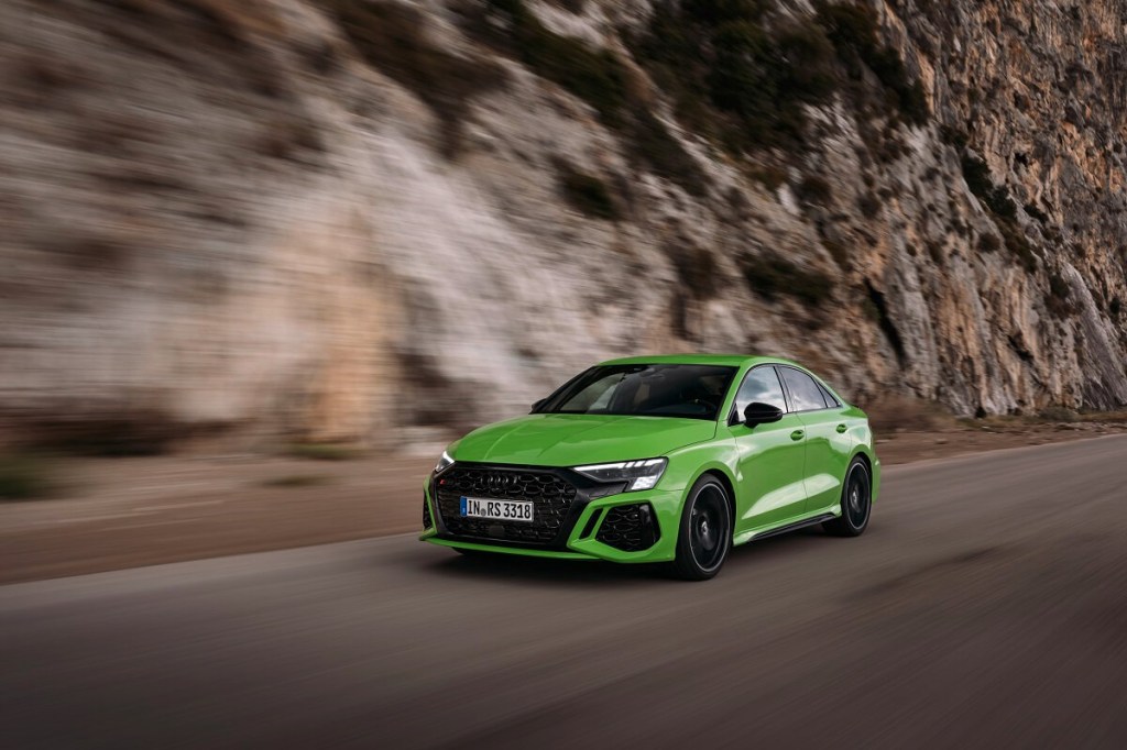 A bright-green Audi RS 3 drives down a mountain pass. 
