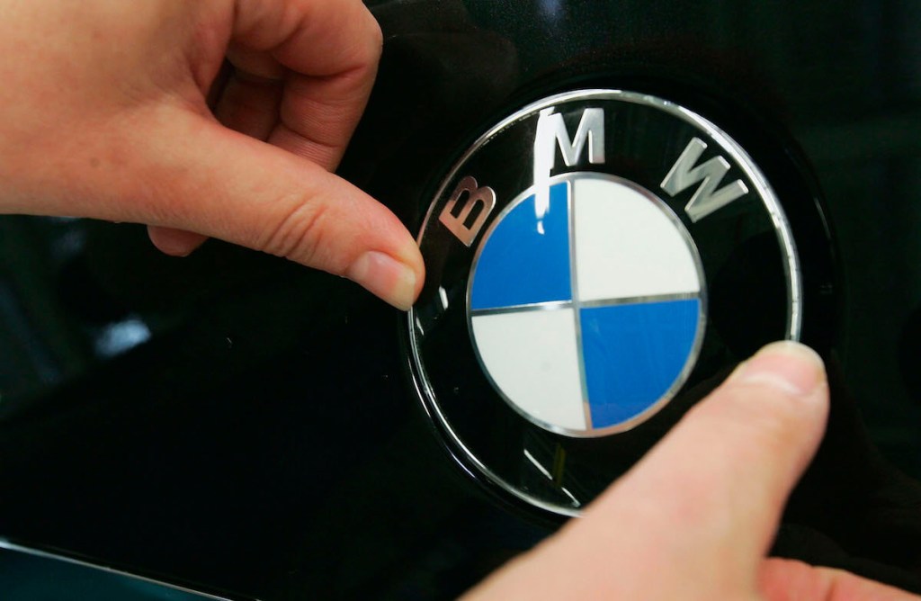 A person presses on a BMW on a badge.