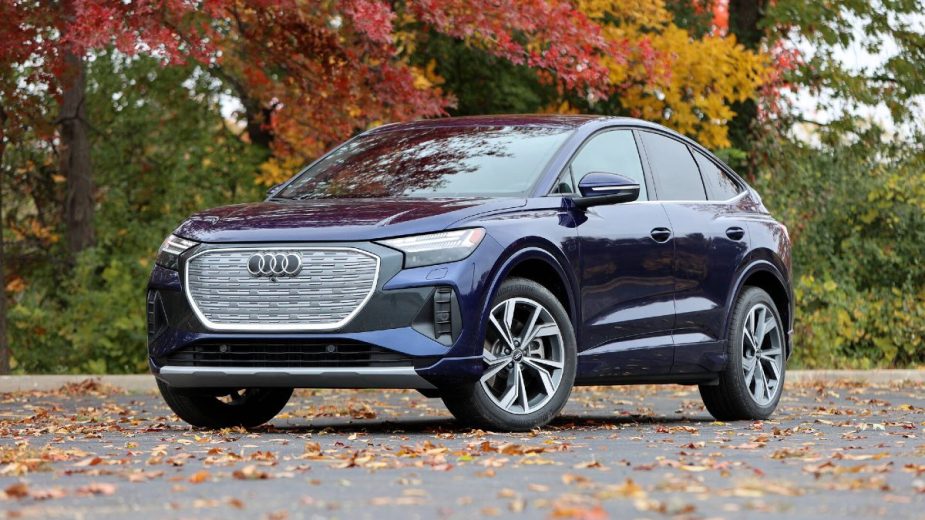 Blue 2023 Audi Q4 e-tron - This electric Audi SUV is posed in front of an autumn tree with leaves that have changed colors.