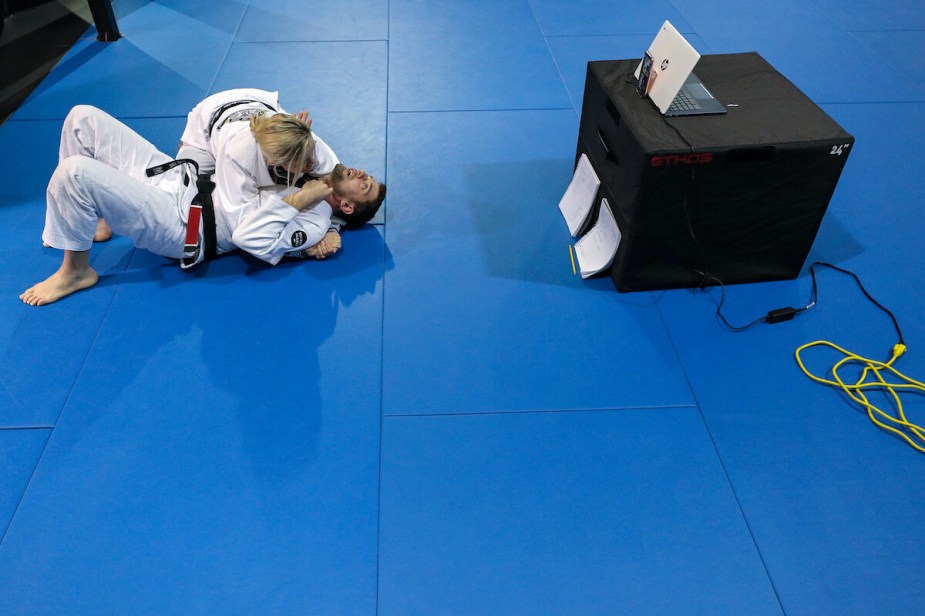 Two Brazilian Jiu-Jitsu practitioners have a match on a mat. 