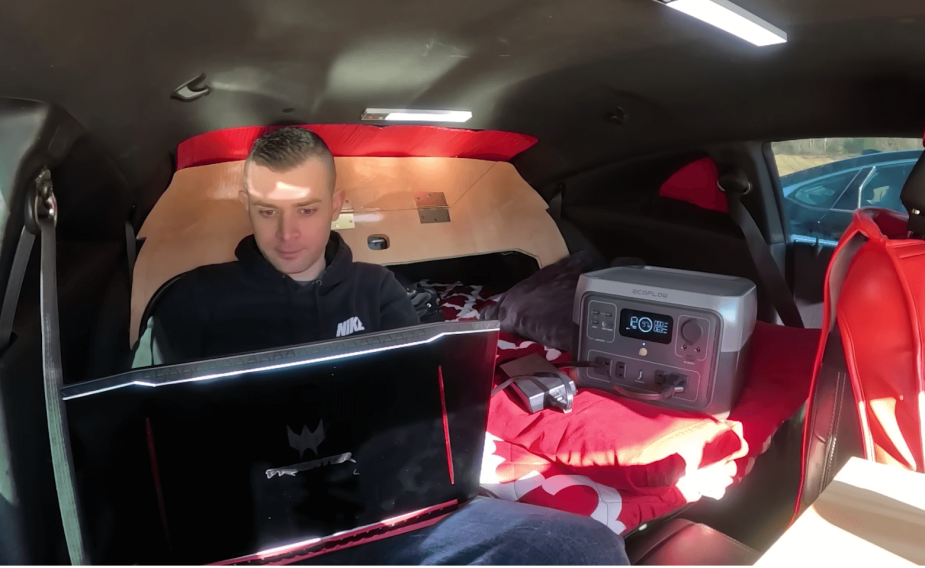 車内でノートパソコンを操作するカマロ キャンパーのオーナー。