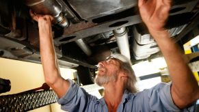 A mechanic working on a cars catalytic converter.