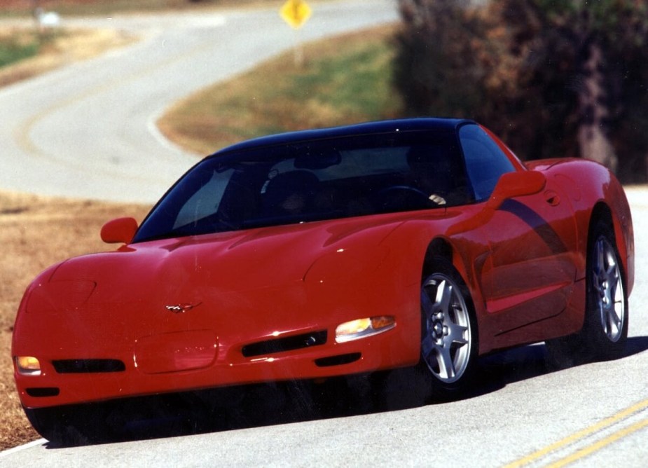 A bright red C5 Corvette corners on twisty roads.
