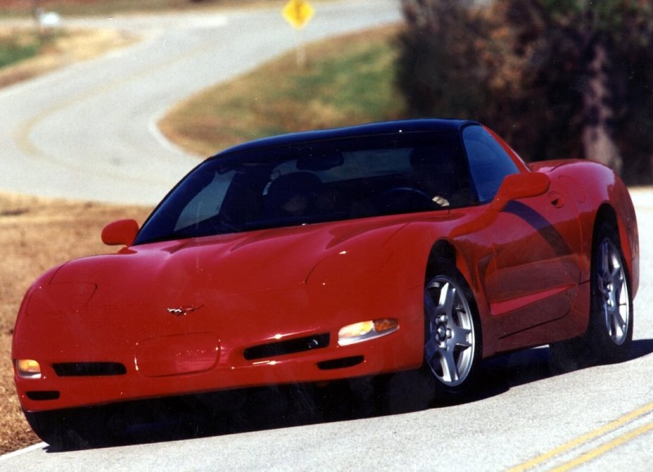 A bright red C5 Corvette corners on twisty roads. 