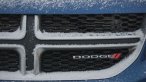 The Dodge emblem on the front of a snowy car grille