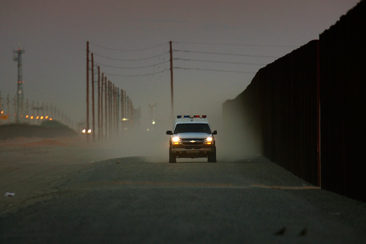 border patrol vehicle driving along a fence line