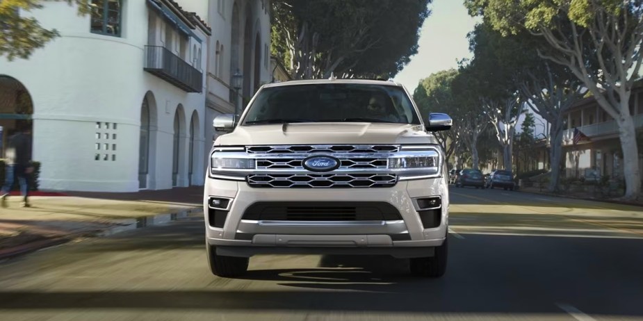 A white 2023 Ford Expedition MAX is driving on the road. 