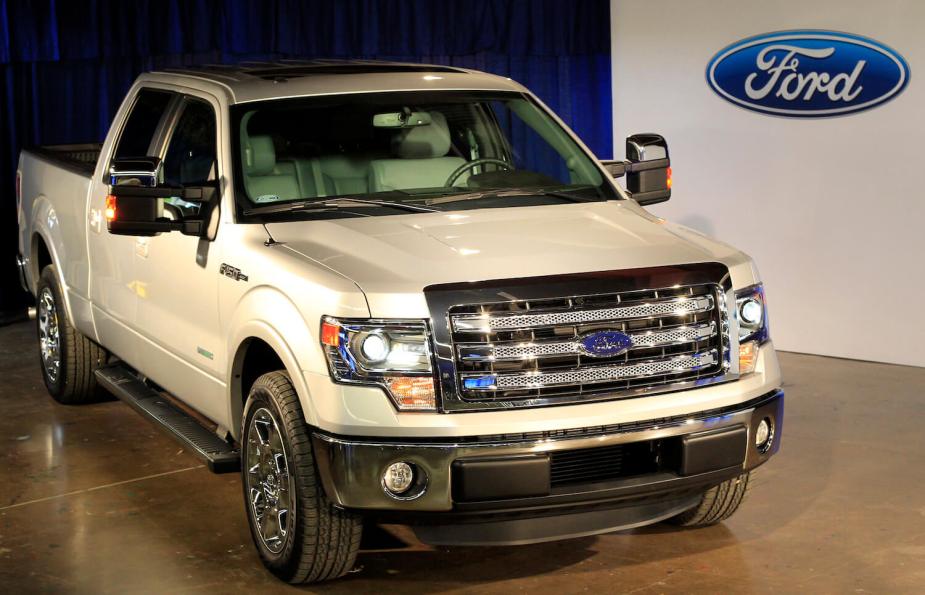 A white Ford F-150 parked on stage during an auto show.
