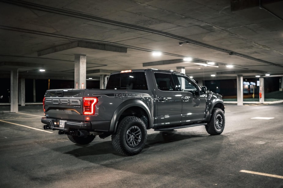 New Gray Ford F-150 Raptor supertruck parked in an indoor parking garage at night.