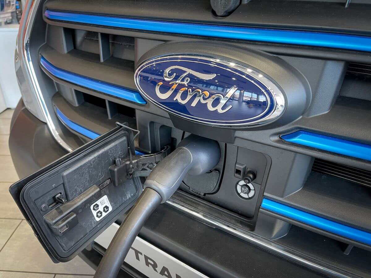 The grille of a Ford E-Transit cargo and work van model plugged into an outlet and charging at a dealership