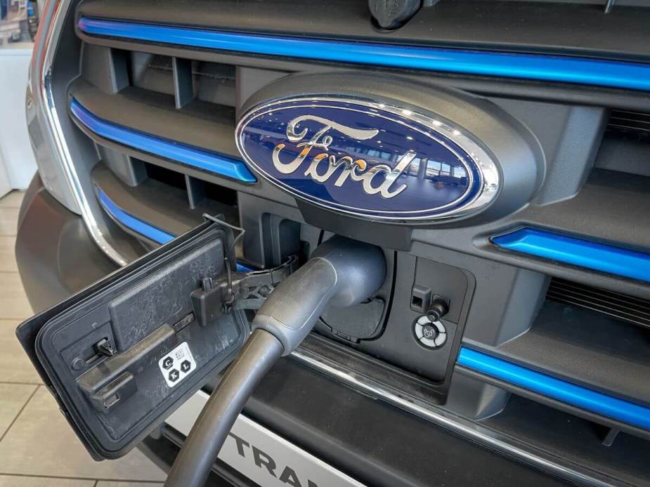 The grille of a Ford E-Transit cargo and work van model plugged into an outlet and charging at a dealership