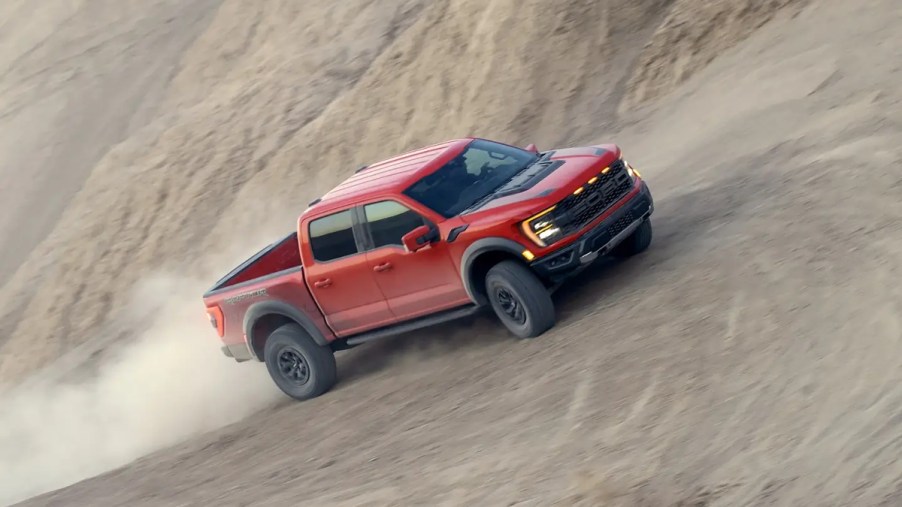 A 2023 Ford F-150 Raptor drives through the sand as a full-size truck.