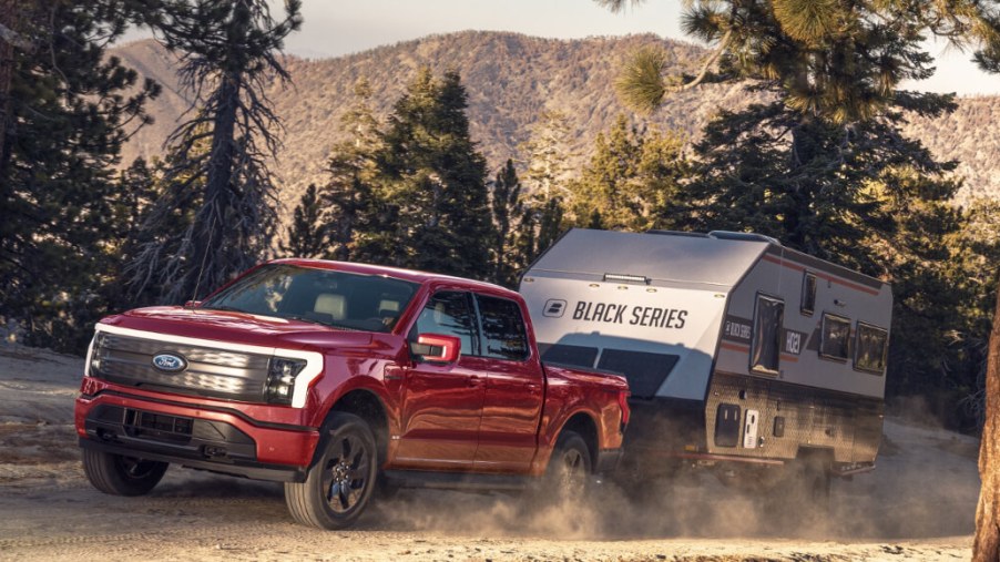 A 2023 Ford F-150 Lightning is towing a trailer behind it as an electric truck.