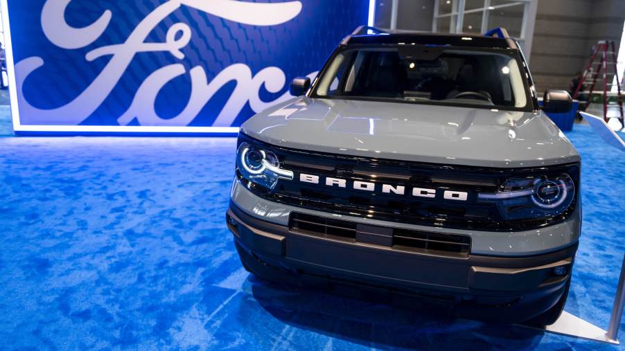 Front-on view of grey Ford Bronco Sport in front of a large Ford logo set on blue carpet.
