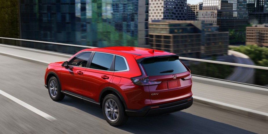 A red 2023 Honda CR-V small SUV is driving on the road. 